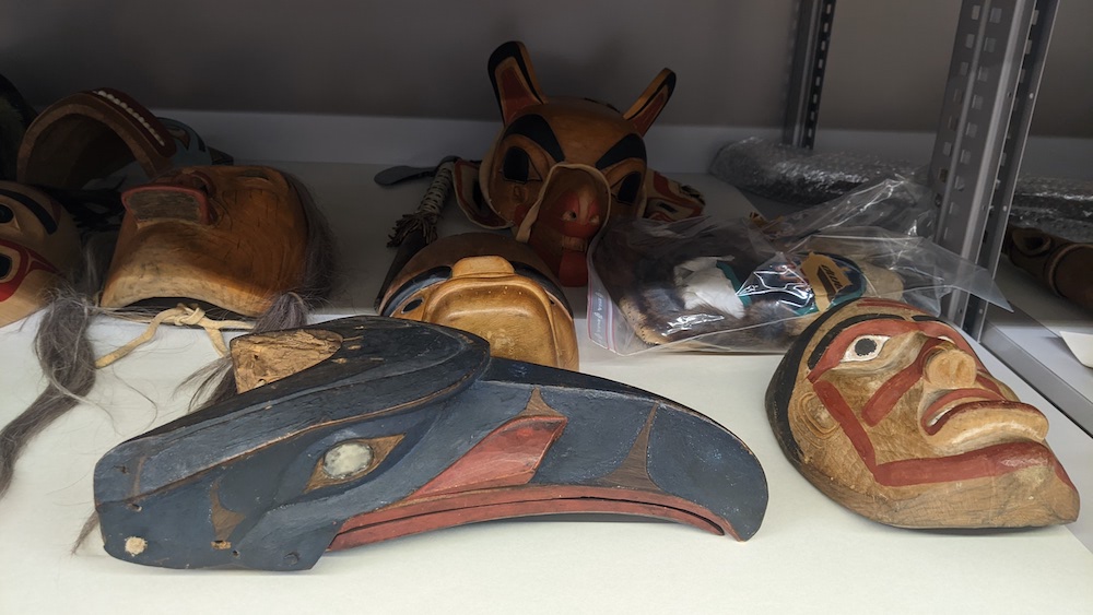 Image: Several masks are lying in a storage shelf, partly wrapped in a plastic bags.