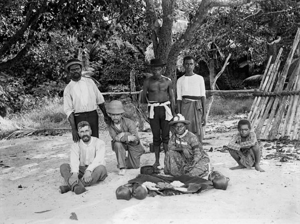 Article Image: Picnic on the beach at Dauar, Torres Strait, 14 May 1898. Haddon seated on the left with (l-r) Pasi, Ray, probably Koriba, Mrs Canoe, unknown youth, and Poi Pasi (squatting). Museum of Archaeology & Anthropology, University of Cambridge, Acc. No. N.23140.ACH2. Photo: MAA.